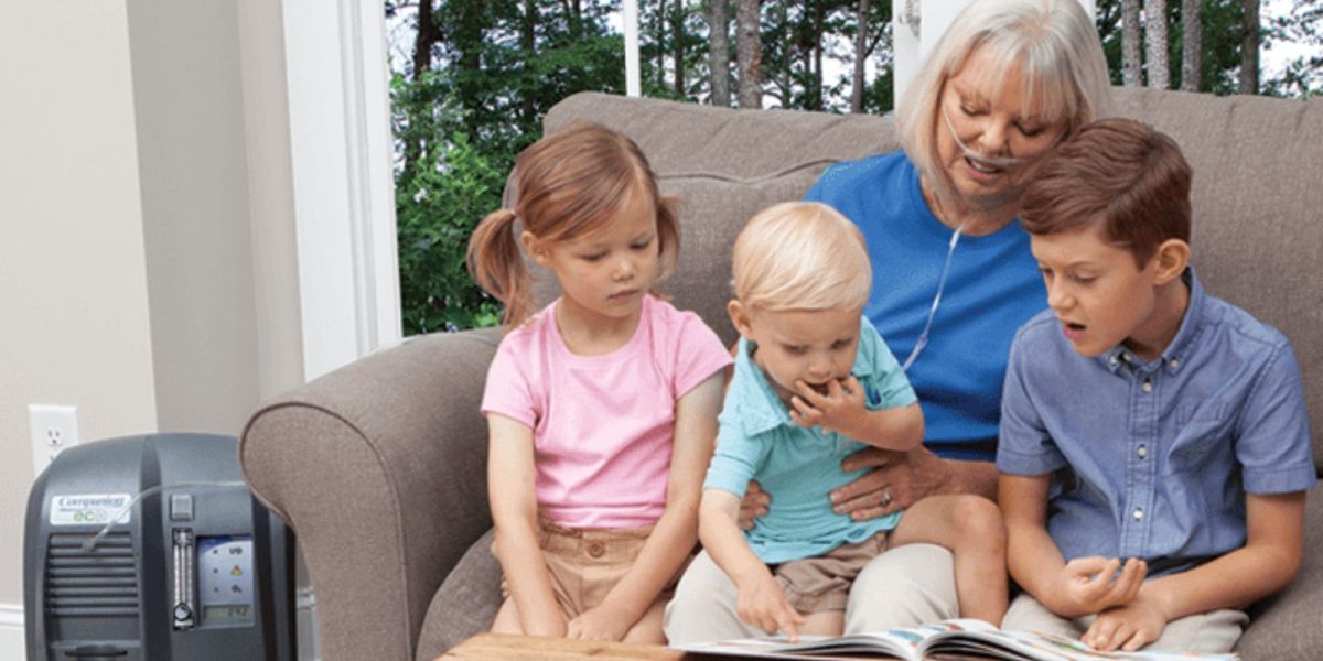 Older woman using a home oxygen concentrator while spending time with her grandchildren