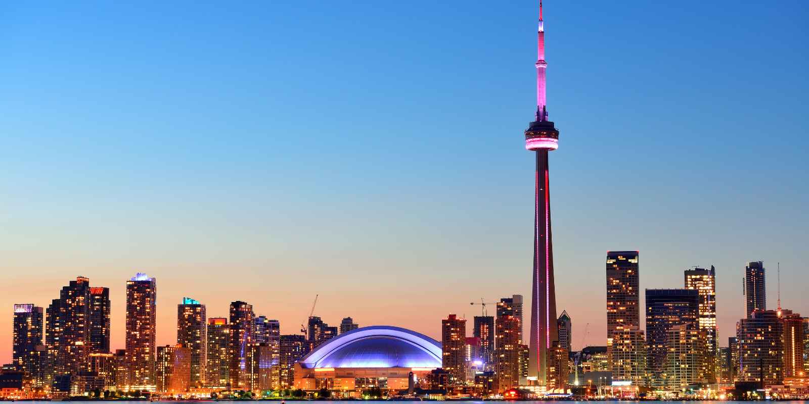 Toronto Ontario skyline at dusk featuring the CN Tower and Rogers Centre